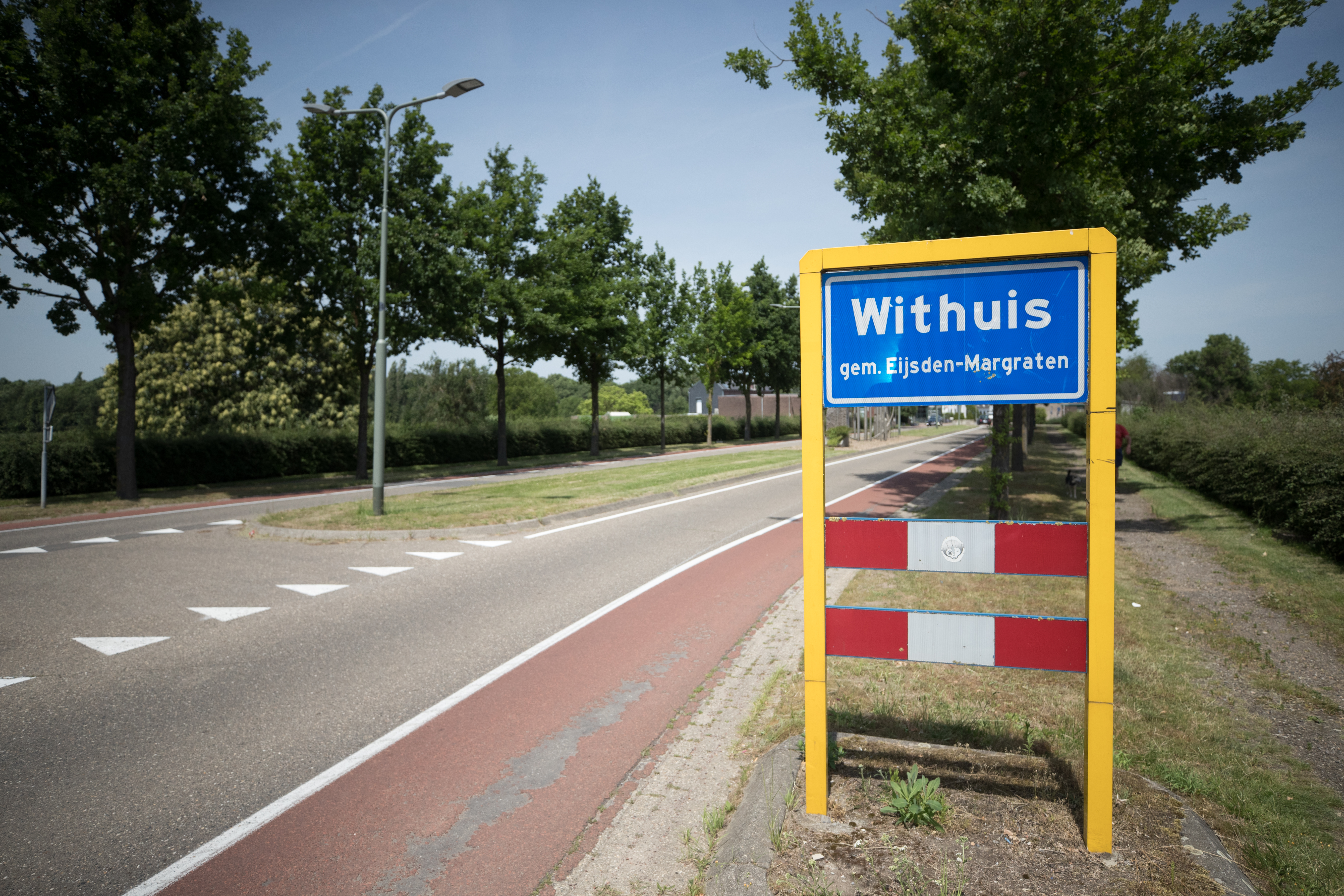 Voormalige grensovergang bij Withuis met bomen langs de weg en een dorpaanduiding, een bord waarop Withuis gemeente Eijsden-Margraten staat